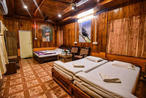 two beds in a room with wooden walls at Aranya Jungle Resorts in Lataguri