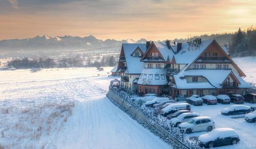 a large house with cars parked in the snow at Hotel Górski in Białka Tatrzanska