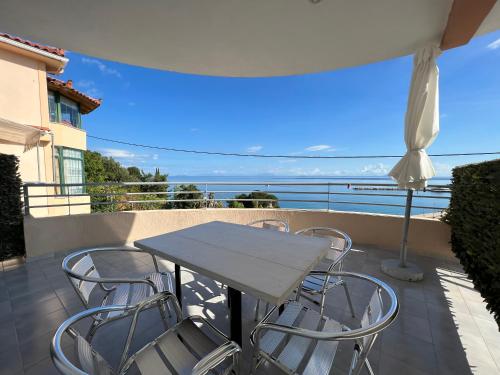 a table and chairs on a balcony with a view of the ocean at Harbour View - Oceanis Apartments in Poros