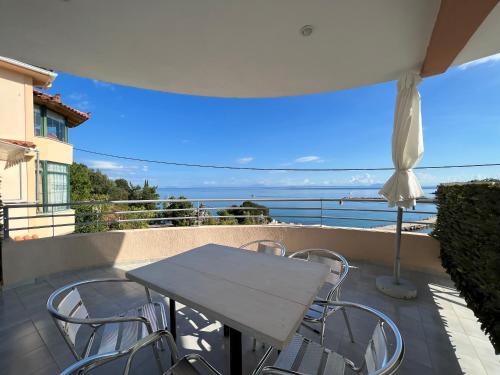 a table and chairs on a balcony with a view of the ocean at Harbour View - Oceanis Apartments in Poros