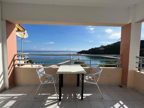 a table and chairs on a balcony with a view of the ocean at Harbour View - Oceanis Apartments in Poros