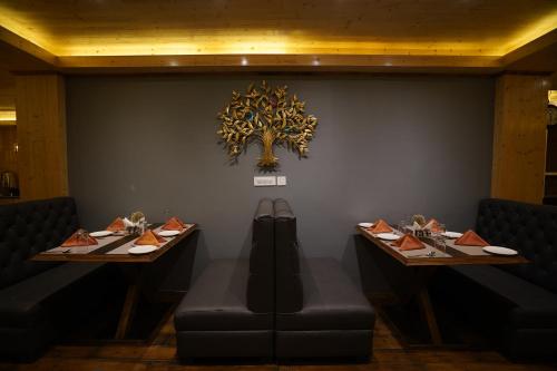 a dining room with two tables and a tree on the wall at Mount Magnolia Boutique Hotel & Spa in Pelling