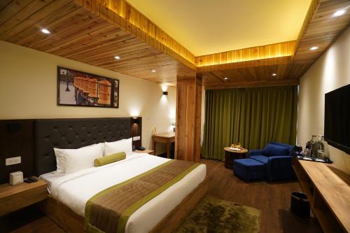 a bedroom with a large bed and a blue chair at Mount Magnolia Boutique Hotel & Spa in Pelling