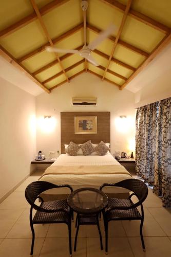 a bedroom with a large bed with two chairs at Hummingbird Resort in Mount Ābu