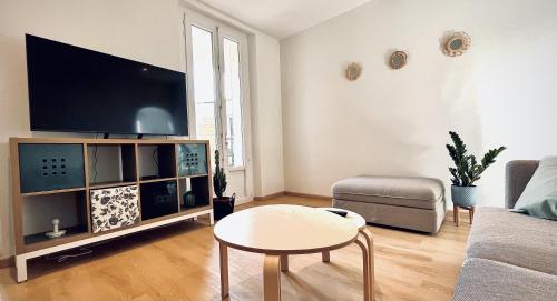 a living room with a tv and a table and a couch at Maison de ville tout confort à Cannes et à 10 Minutes à pied de la plage in Cannes