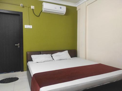 a bedroom with a bed with a green wall at Homecation SP Lodge in Nowgong