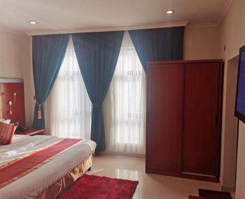 a bedroom with a bed and blue curtains and a tv at Villa Park in Al Khobar