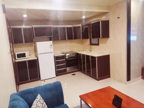 a small kitchen with brown cabinets and a blue couch at Villa Park in Al Khobar