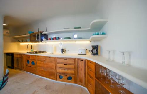 a kitchen with wooden cabinets and a counter with wine glasses at Alterhome Swan villas with swimming pool and ocean views in Placencia Village