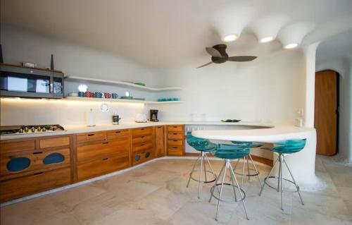 a kitchen with a table and some blue stools at Alterhome Swan villas with swimming pool and ocean views in Placencia Village