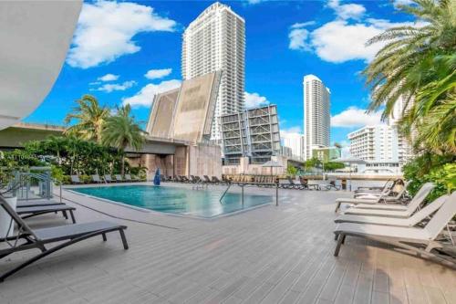 a swimming pool with chaise lounge chairs and buildings at Amazing 1B-1B Apartment With Amazing View! in Hallandale Beach