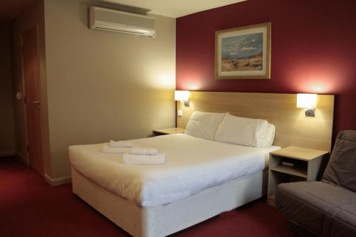 um quarto de hotel com uma cama e um sofá em The Welcome Inn Rotherham/Sheffield em Rotherham