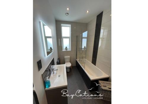 a bathroom with a tub and a sink and a bath tub at Stylish 2 bed Paignton apartment, 5 minute walk to beach in Paignton