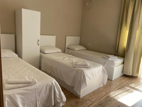 a room with three beds with white sheets at nira hotel in Gonio