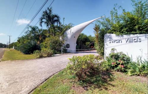 a sign in front of a building on a road at Alterhome Swan villas with swimming pool and ocean views in Placencia Village