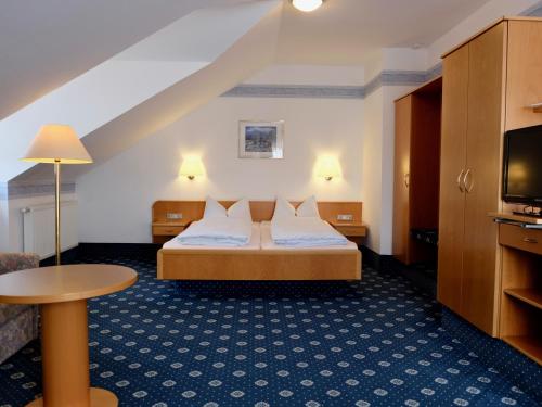 a hotel room with a bed and a tv at Gästehaus Biedermann in Kinding