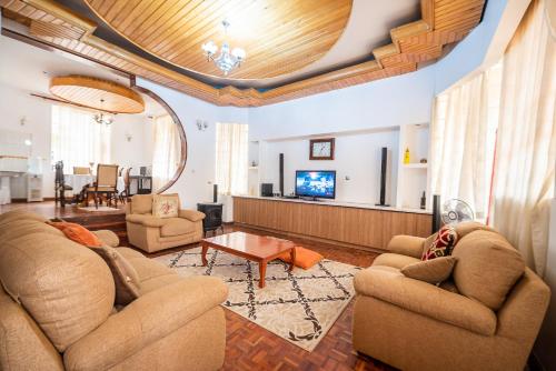 sala de estar con 2 sofás y TV en spacious & stylish 4bdr kileleshwa en Nairobi
