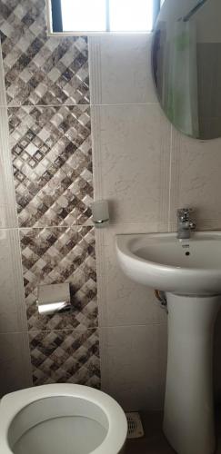 a bathroom with a toilet and a sink and a mirror at Sochati Casa Resort in Nairobi