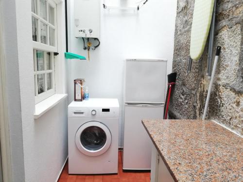 a kitchen with a washing machine and a refrigerator at Alojamento Local Ferros - Duplex in Viana do Castelo