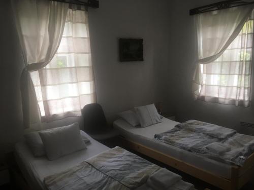 two beds in a room with two windows at Kiss Apartman Uppony in Uppony