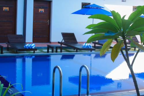 a pool with chairs and a palm tree next to it at Ali Weta Safari Resort in Udawalawe