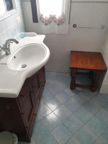 a bathroom with a sink and a wooden stool at Kalimaka Bed & Breakfast in Scario