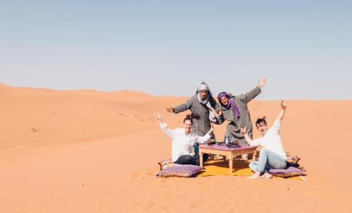 a group of people sitting in the desert at Mhamid camp activités in Mhamid