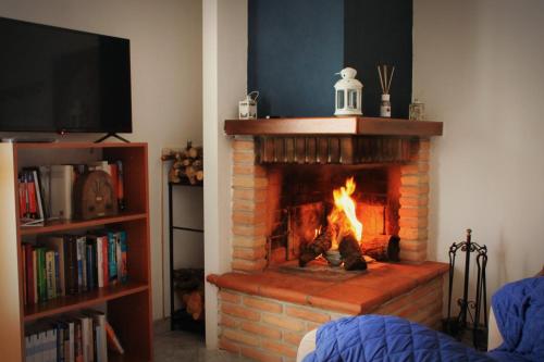 a living room with a brick fireplace with a fire at Mansarda con camino in Montefranco