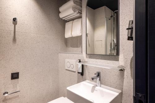 a white bathroom with a sink and a mirror at Hôtel de France Gare de Lyon Bastille in Paris