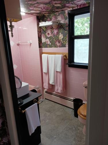 a pink bathroom with a toilet and a window at The guest house at the regina house tea room in Moosic