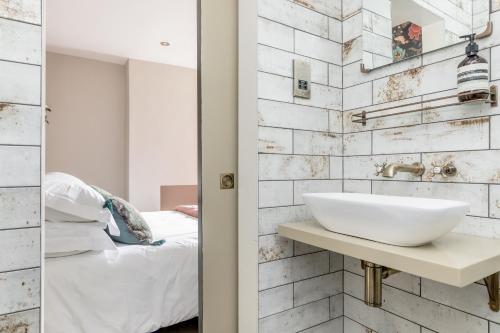 uma casa de banho com um lavatório branco e um quarto em The Oak Rooms - Stylish & luxurious stay in Sussex by Huluki Sussex Stays em Hurstpierpoint