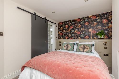 1 dormitorio con 1 cama grande y pared de flores en The Oak Rooms - Stylish & luxurious stay in Sussex by Huluki Sussex Stays en Hurstpierpoint