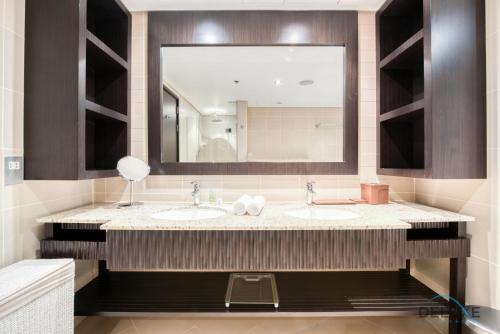 a bathroom with two sinks and a large mirror at Paradise 2BR at Royal Amwaj North Palm Jumeirah by Deluxe Holiday Homes in Dubai