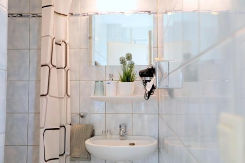 a white bathroom with a sink and a mirror at Hotel St. Peter in Dormagen