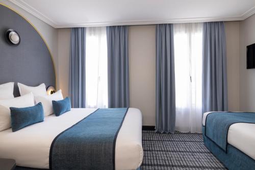 a hotel room with a large bed and two windows at Hôtel de France Gare de Lyon Bastille in Paris