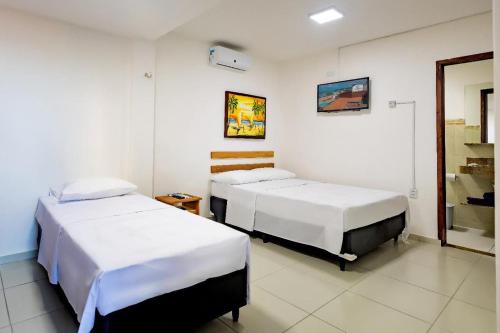 a room with two beds and a mirror at Encanto da Praia hotel pousada in Natal