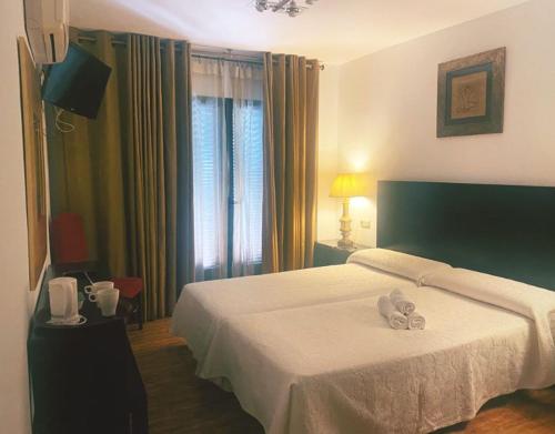 Una habitación de hotel con una cama con dos toallas. en Hostal Tres Soles, en Nerja