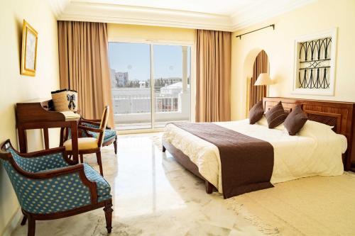 a bedroom with a bed and a desk and a chair at TMK Flora Park by Turismark - Adults Only in Hammamet