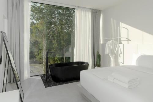 HER HUAHIN POOL VILLA في هوا هين: غرفة نوم مع حوض استحمام أسود ونافذة كبيرة