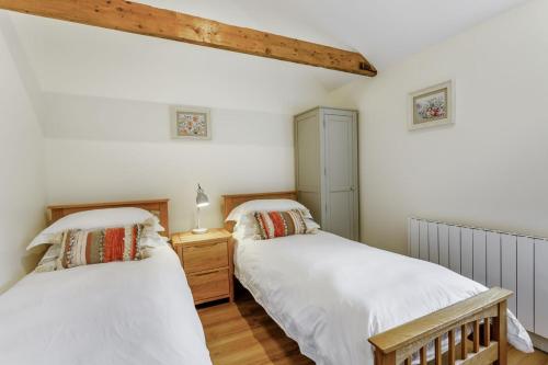 Habitación con 2 camas, paredes blancas y suelo de madera. en Woodpecker Barn - Uk38613, en Wisbech