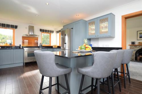 a kitchen with blue cabinets and bar stools at Kennacraig Lodge in Whitehouse