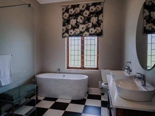 a bathroom with a tub and two sinks and a window at Bontebokskloof Manor in Swellendam