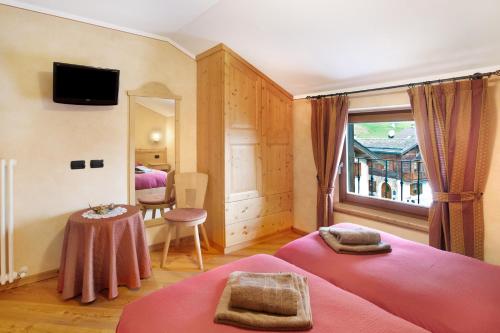 een slaapkamer met 2 bedden, een tafel en een raam bij Baita Aris Appartamento Ables in Livigno