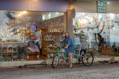 una mujer montando una bicicleta delante de una tienda en Kidi's Lodge Gilitrawangan, en Gili Trawangan