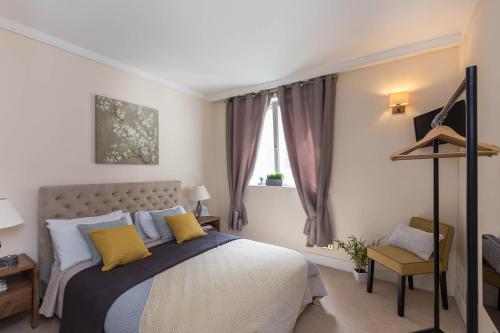 a bedroom with a bed with yellow pillows and a window at Park Lane Apartments - Clarges Street in London