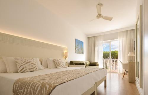 a bedroom with a large bed and a balcony at Hotel Castell dels Hams in Porto Cristo