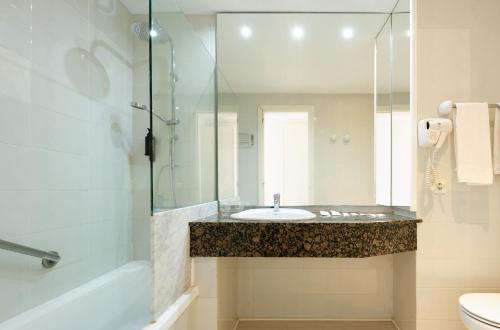 a bathroom with a sink and a glass shower at Hotel Castell dels Hams in Porto Cristo