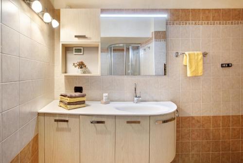 ein Bad mit einem Waschbecken und einem Spiegel in der Unterkunft Baita Aris Appartamento Canton in Livigno