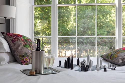 a white bed with a table with bottles and a window at The Goodenough Hotel London in London