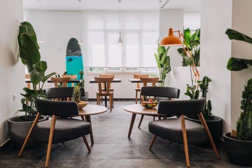 a room with tables and chairs and plants at Dave by the Beach Loutraki in Loutraki